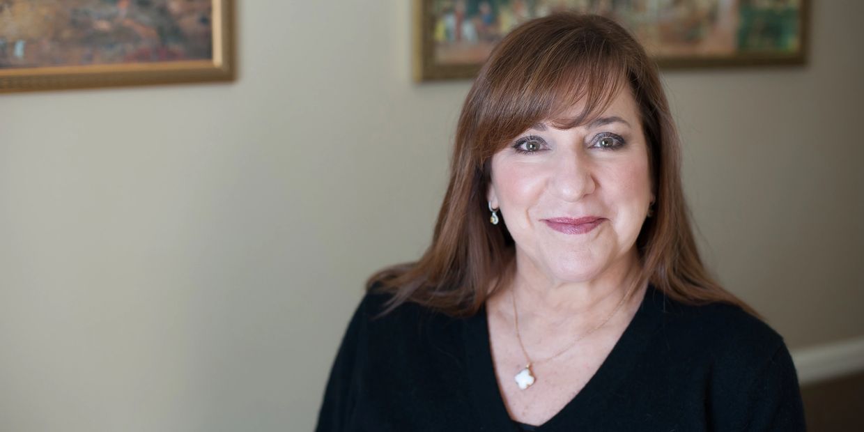 Smiling woman with brown hair and subtle makeup wearing a black top.