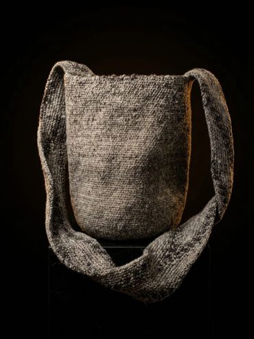 Handcrafted gray knit shoulder bag with a wide strap.