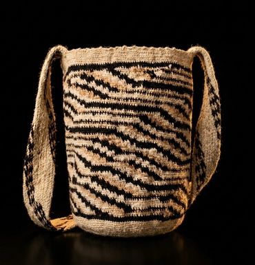 Handwoven bag with black and beige geometric patterns and a wide strap.