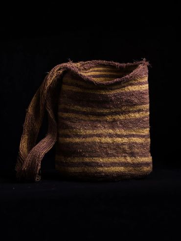 Woven striped bag with a single strap against a black background.