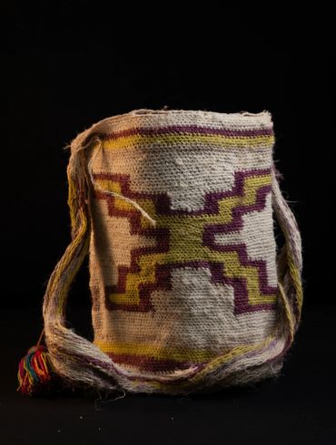Handwoven bag with geometric patterns in yellow and purple on cream.