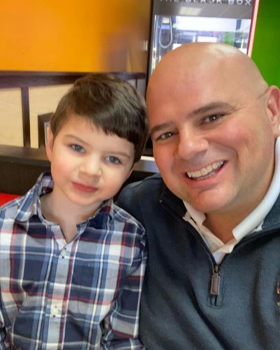 Smiling man and young boy sitting closely in a casual setting.