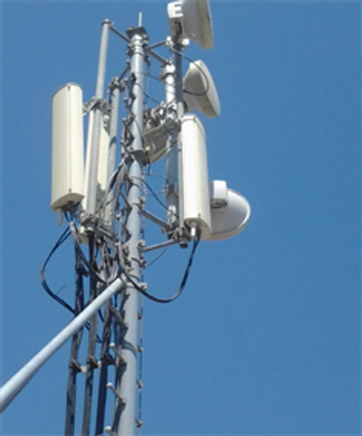 Telecommunication antenna tower against a clear blue sky.