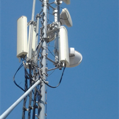 Close-up of a telecommunications antenna tower against a clear blue sky.
