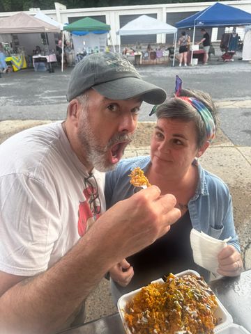 Couple enjoying food at outdoor market.