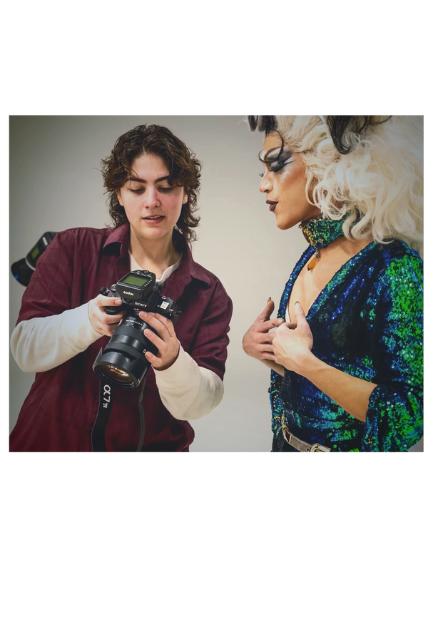 Photographer showing a photo to a drag queen in colorful outfit and makeup.