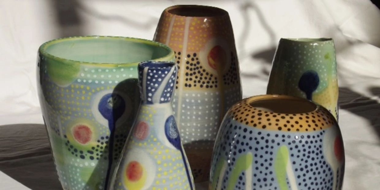 Colorful ceramic vases with dotted and abstract patterns arranged on a white surface.