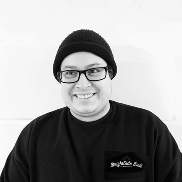 Smiling person wearing glasses and a black beanie.