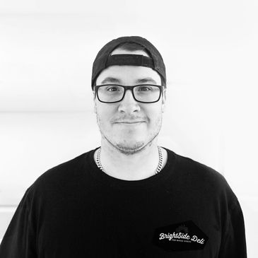 Man wearing glasses and cap smiling.