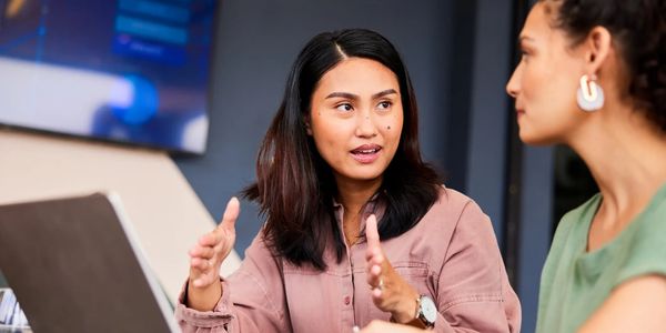 two women chatting in front of a laptop computer