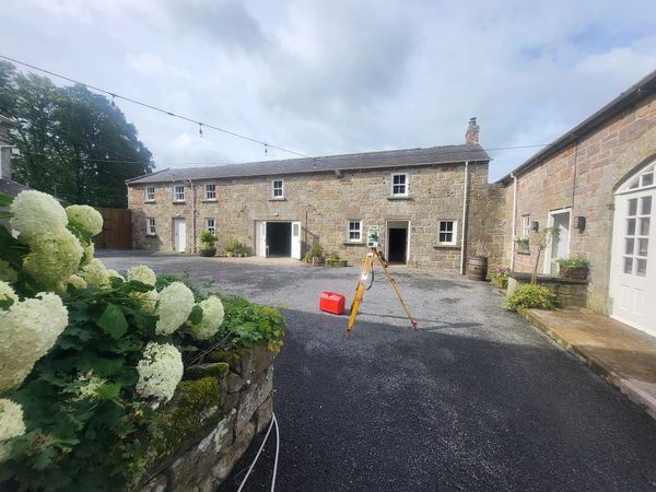 Stone buildings surrounding a paved courtyard with surveying equipment.