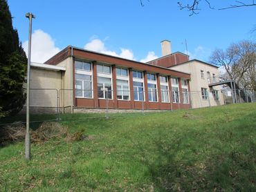 Exterior view of a mid-century school building under blue sky.