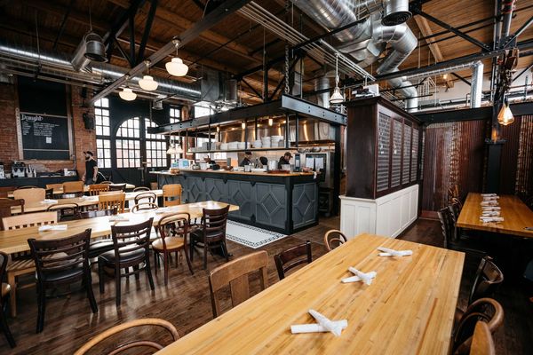 Open kitchen, commercial ventilation, stainless equipment, & industrial fixtures in a modern space.