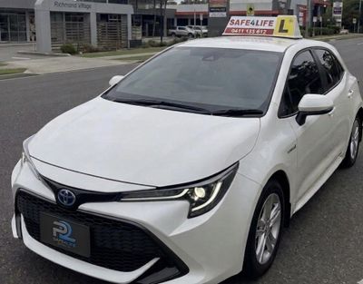White Toyota driving school car parked on the street.