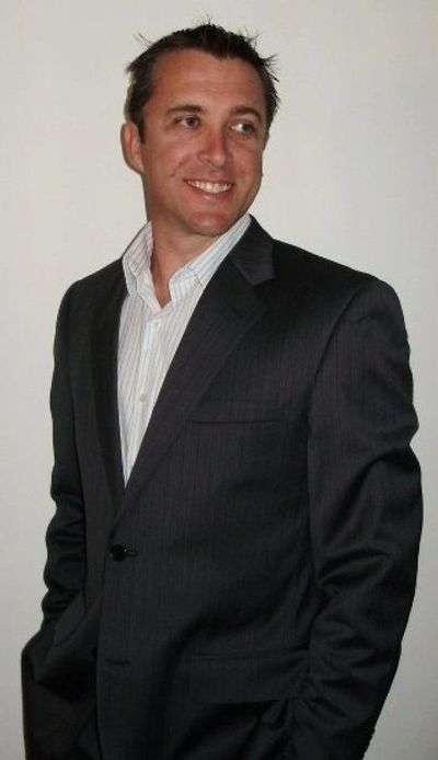 Man in a dark suit smiling and looking to the side.