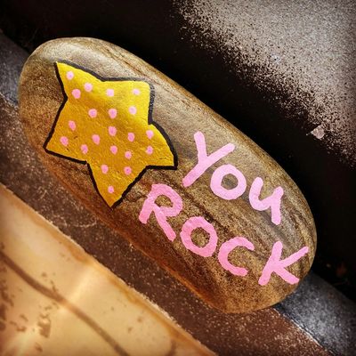  A smooth rock, with a picture of a star and the words "you rock' painted on it