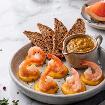 Shrimp appetizers on mango puree with whole grain crackers and dipping sauce.