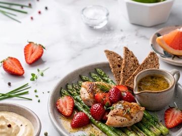 Grilled chicken with asparagus and strawberries, served with sauce and rye bread.