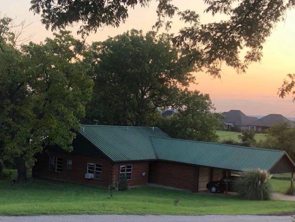 House with green roof at sunset surrounded by trees.