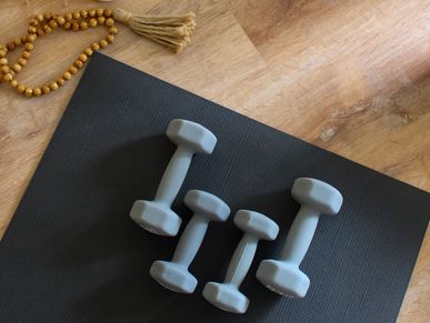 Four gray dumbbells on a black yoga mat.