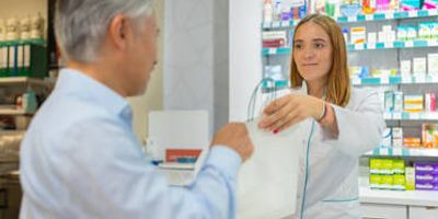 Pharmacist handing a prescription bag to a male customer at a neighborhood pharmacy in Philadelphia.