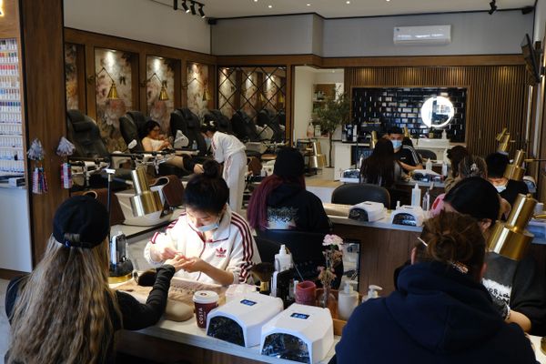 Busy nail salon with customers getting manicures and pedicures.