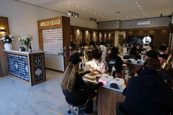 A modern nail salon with clients getting manicures at multiple stations.