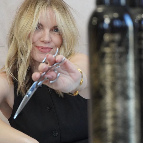 Woman holding scissors and smiling.