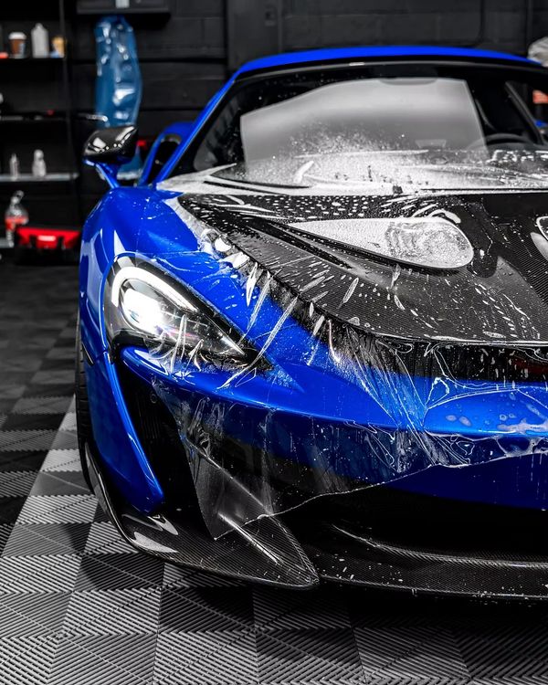 Blue sports car with protective film being applied.