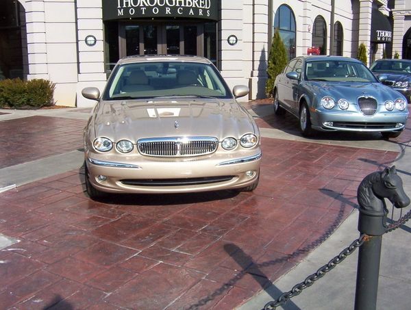Two luxury cars parked outside Thoroughbred Motorcars dealership.