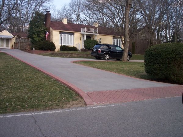 A suburban house with a curved driveway and a parked black SUV.