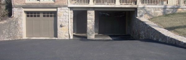 A house with three distinct garage doors and stone walls.