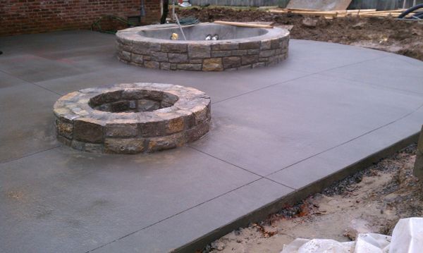Two stone fire pits on a newly poured concrete patio.