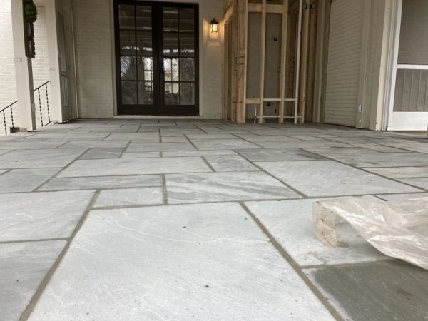 Newly installed stone tile floor on a porch with double doors.
