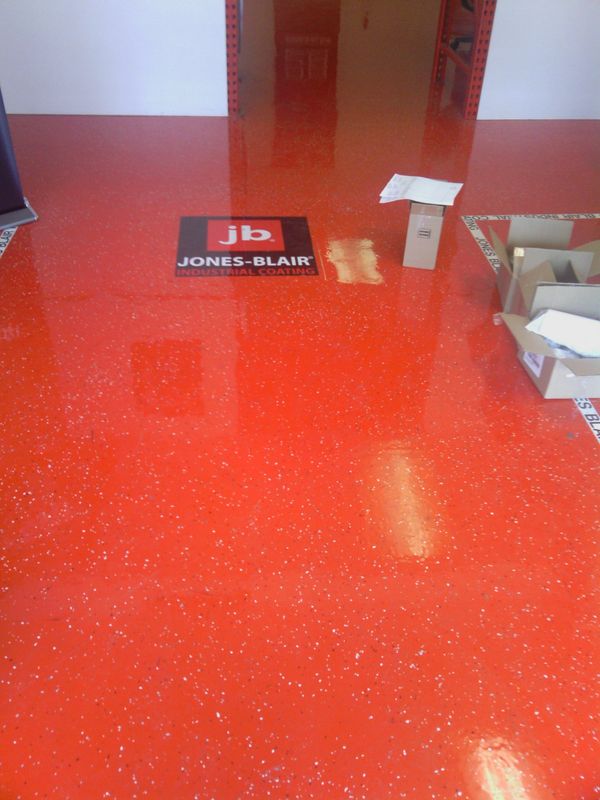 Glossy red industrial floor with Jones-Blair logo and scattered boxes.