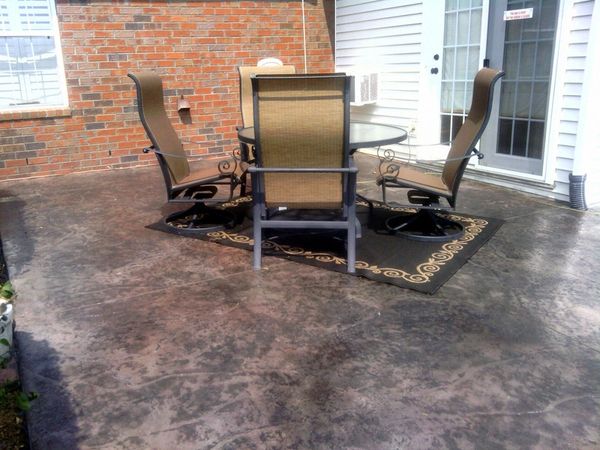 Outdoor patio set with four chairs on a decorative rug.