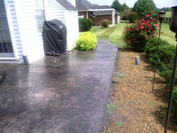 A backyard patio with a covered grill and garden beds alongside.