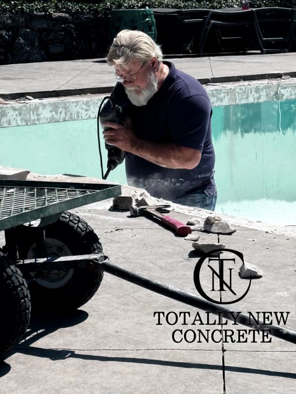 Man using power tool to repair concrete around an empty pool.