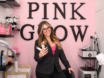 Kylee Swinney standing holding her facial brushes inside her treatment room at Pink Glow Skin by Ky
