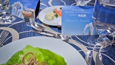 Place setting on a table with a brochure leaning up against a glass. 