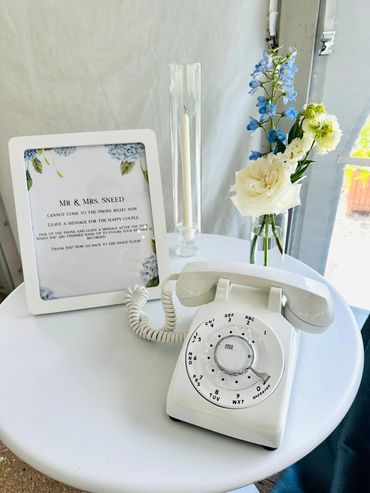 Vintage rotary phone with a floral wedding sign and vase.