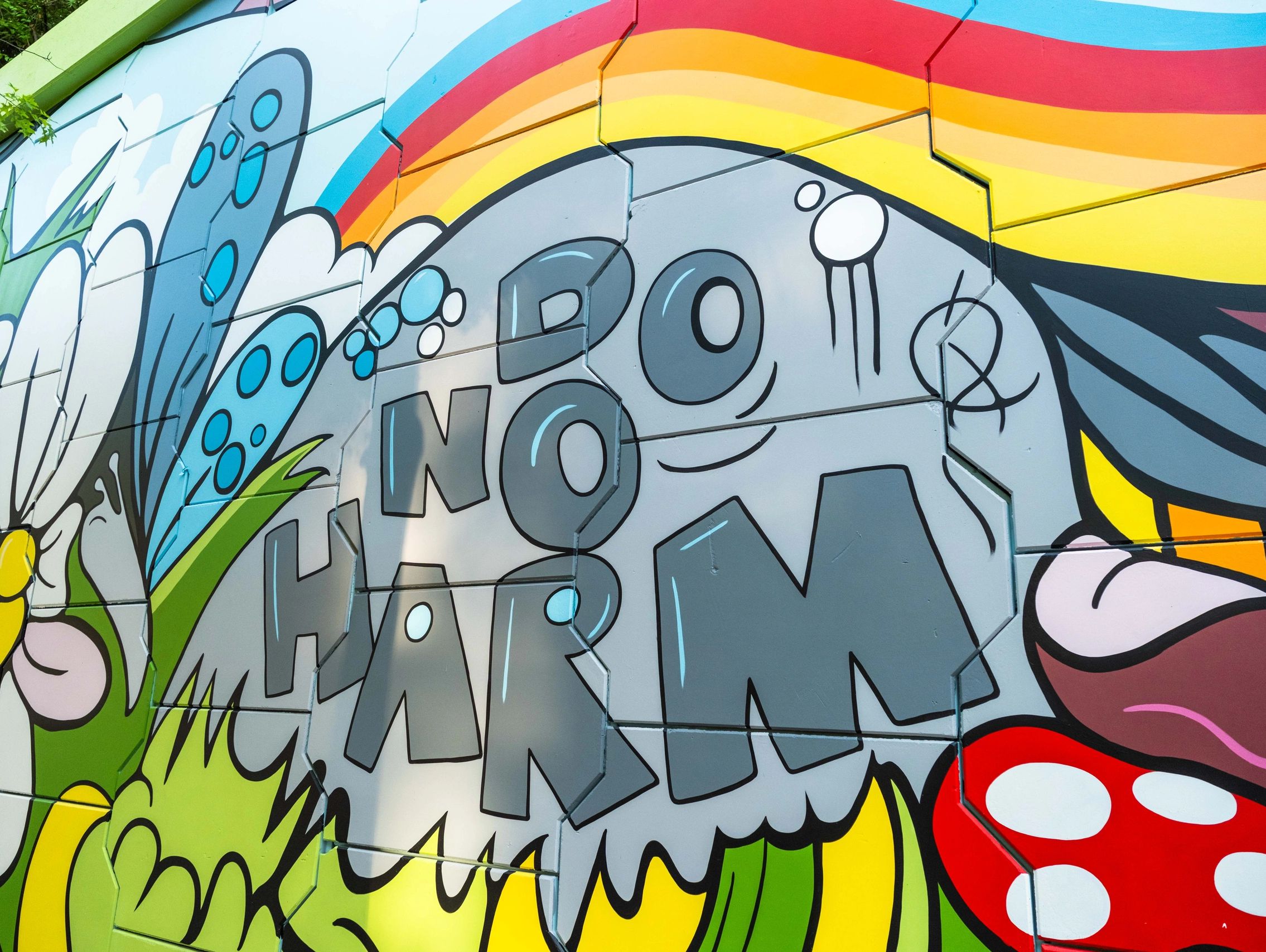 Colorful street art with a rainbow and bold letters on a wall.