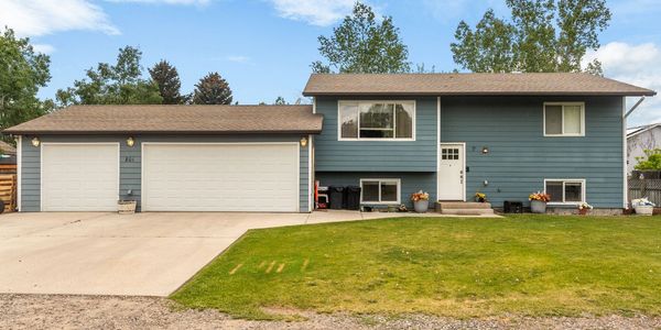 Blue house with a three-car garage and a green lawn.