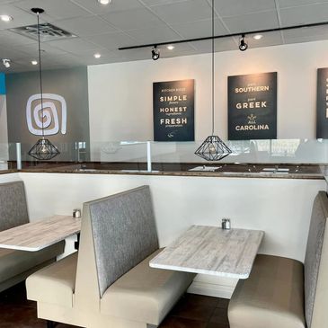 Empty modern restaurant booths with pendant lighting and wall art.