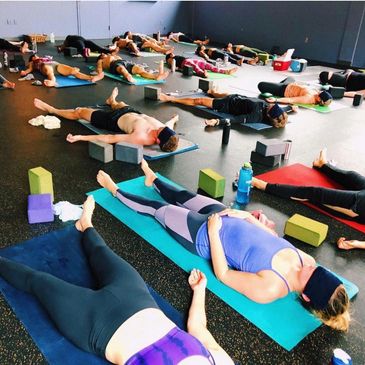 A room of people relaxing as part of a Vinyasa yoga class