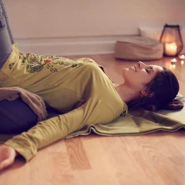 A woman laying back on the floor and deeply relaxed during an in-person class