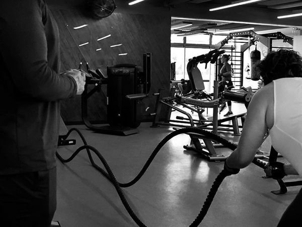 People working out with battle ropes in a gym.