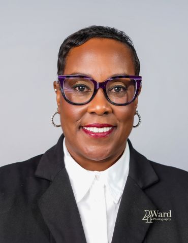 Professional portrait of a woman wearing glasses and a black blazer.