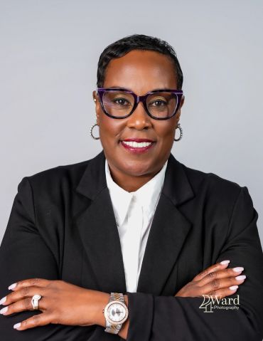 Confident woman in professional attire smiling with arms crossed.