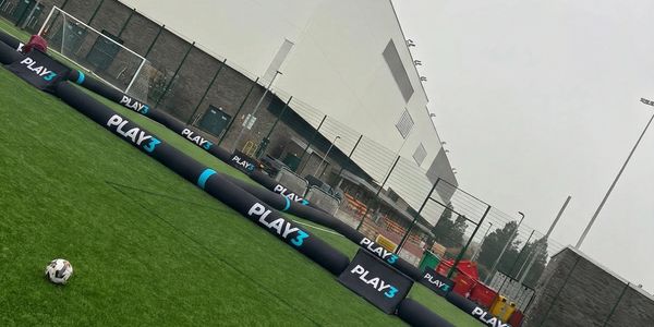 Outdoor artificial turf field with inflatable Play3 Pitch and balls.